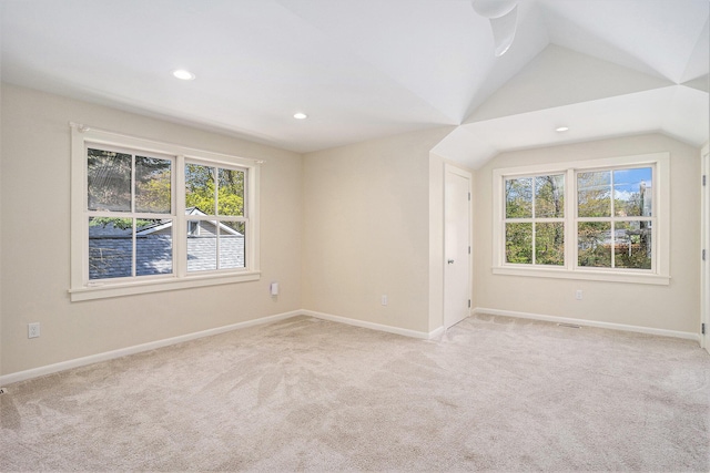 unfurnished room with healthy amount of natural light, light colored carpet, lofted ceiling, baseboards, and recessed lighting
