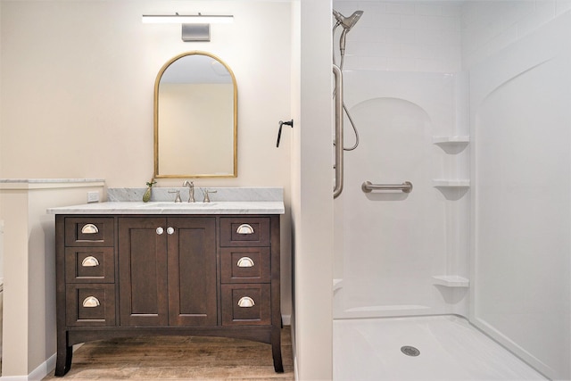 full bath featuring wood finished floors, vanity, and a shower