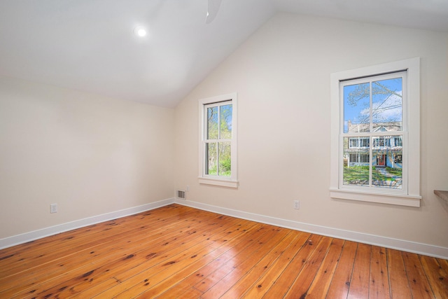 additional living space with light wood-style floors, vaulted ceiling, baseboards, plenty of natural light, and a ceiling fan
