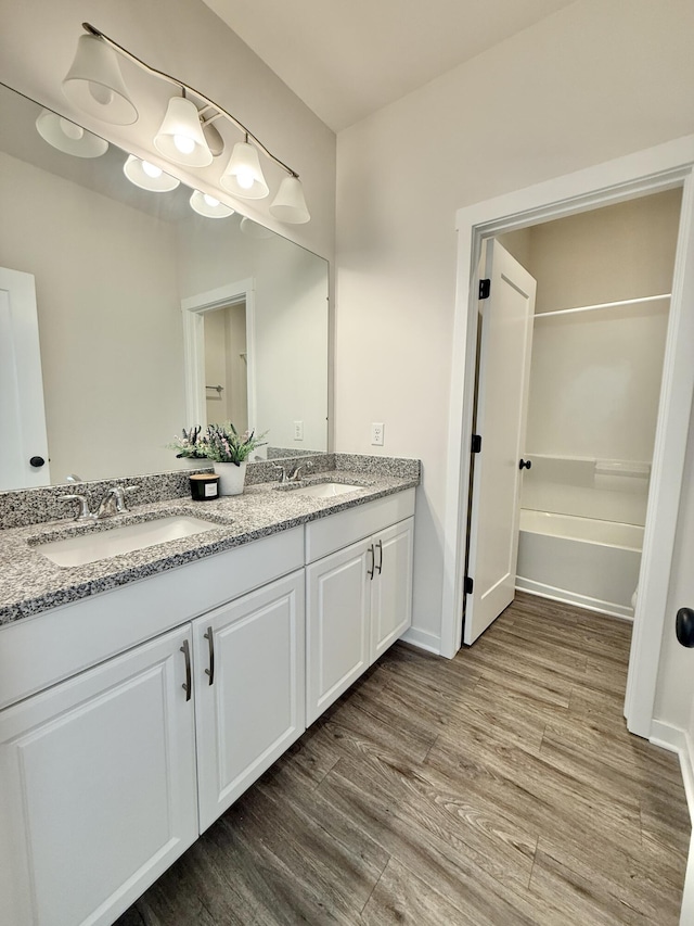full bath with wood finished floors, double vanity, and baseboards