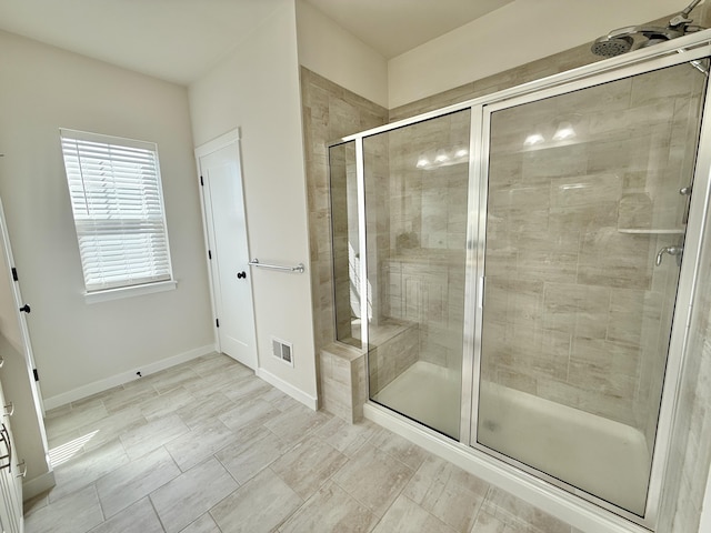 full bathroom with a shower stall and baseboards