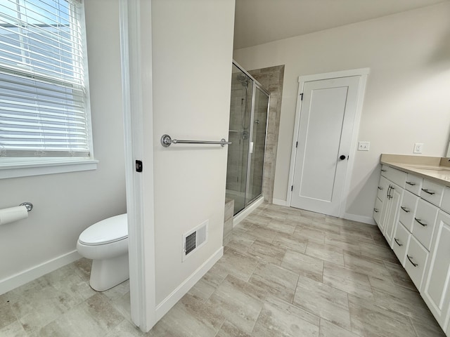 bathroom with a shower stall, vanity, toilet, and baseboards