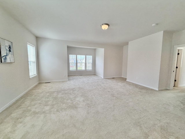 spare room featuring carpet, baseboards, and a smoke detector