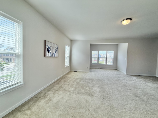 unfurnished room featuring light carpet and baseboards
