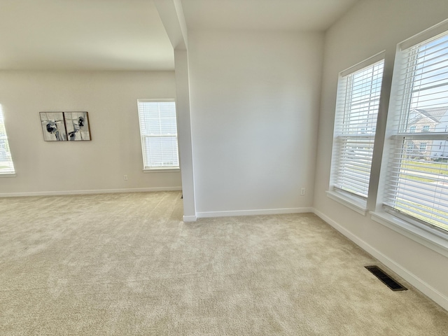 unfurnished room featuring light colored carpet and baseboards