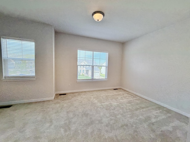 empty room featuring healthy amount of natural light, baseboards, and carpet