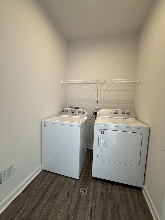 washroom with independent washer and dryer, dark wood-type flooring, and baseboards