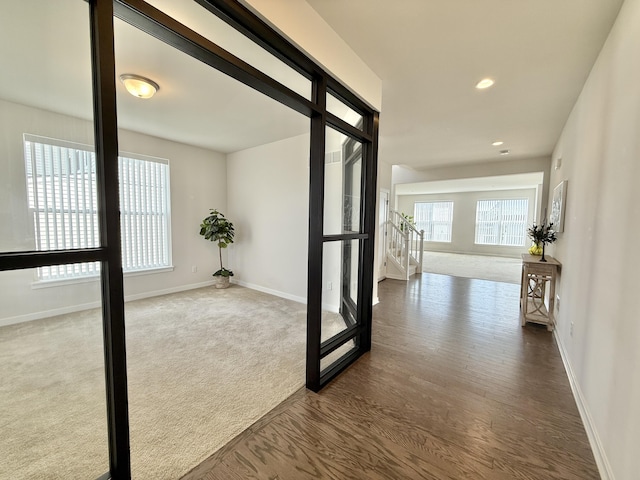 corridor featuring baseboards, dark wood finished floors, recessed lighting, and dark colored carpet