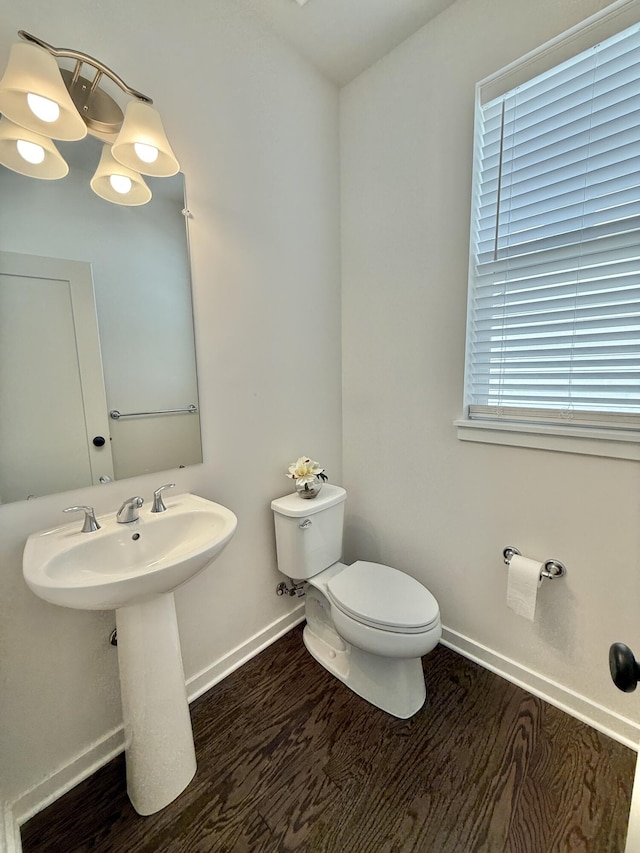 bathroom with toilet, baseboards, and wood finished floors