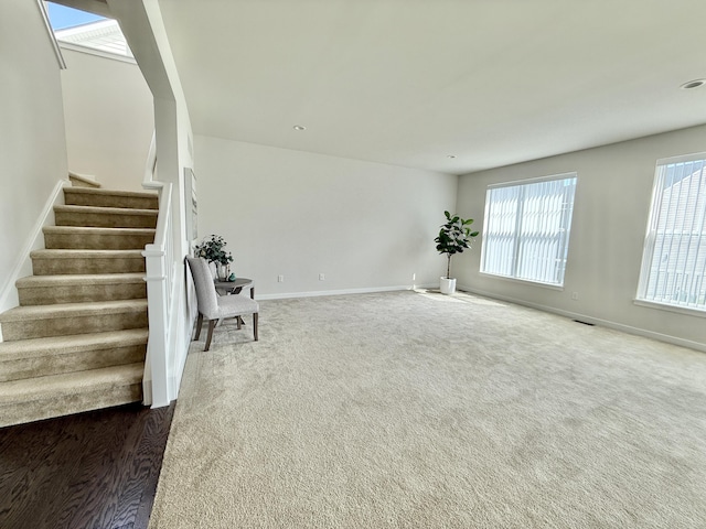 unfurnished living room with stairs, baseboards, and carpet floors
