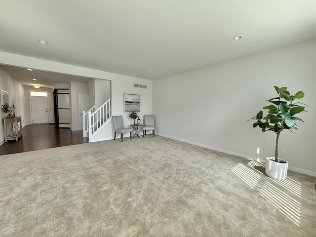 unfurnished living room with dark colored carpet, baseboards, recessed lighting, and stairway