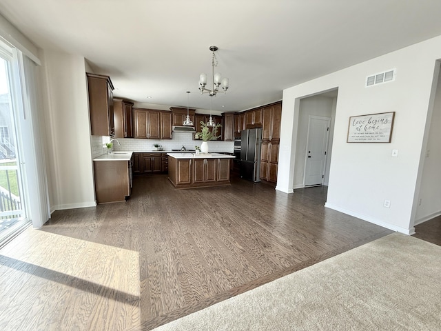 kitchen with freestanding refrigerator, light countertops, a chandelier, and plenty of natural light
