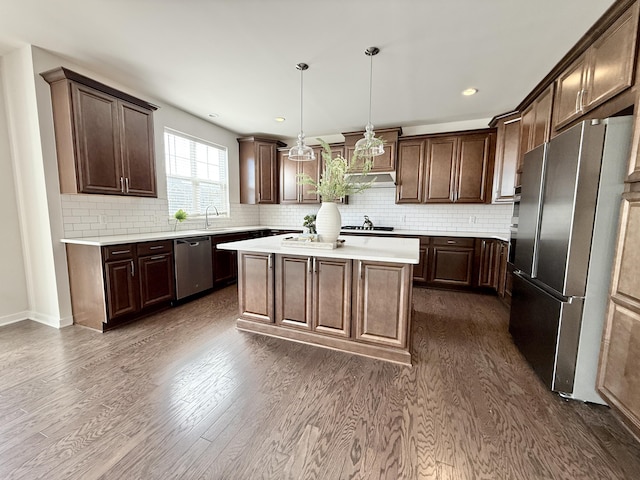 kitchen with appliances with stainless steel finishes, dark wood-style floors, a center island, light countertops, and recessed lighting