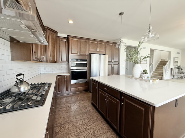 kitchen with ventilation hood, appliances with stainless steel finishes, light countertops, backsplash, and recessed lighting