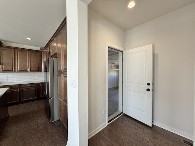 kitchen with freestanding refrigerator, dark brown cabinetry, dark wood-style flooring, light countertops, and recessed lighting