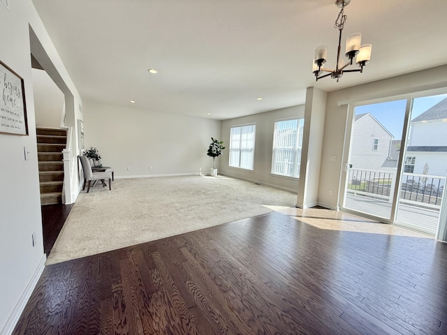 unfurnished living room featuring baseboards, dark wood finished floors, a chandelier, stairway, and recessed lighting