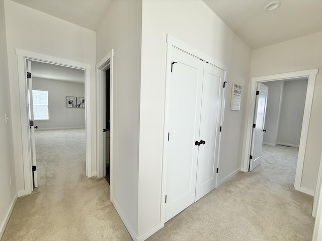 hall with light colored carpet and baseboards