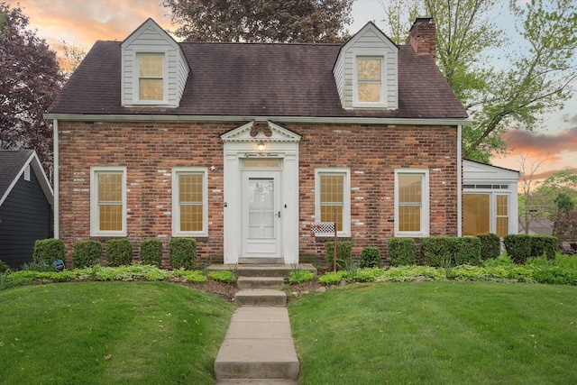 view of front of home featuring a front lawn, brick siding, and a chimney