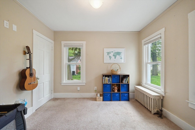 game room featuring radiator heating unit, carpet flooring, ornamental molding, and plenty of natural light