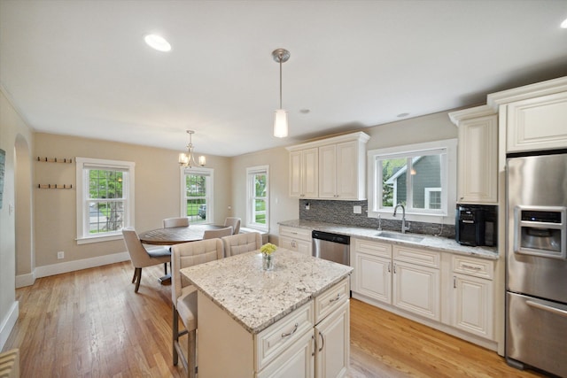 kitchen featuring stainless steel appliances, a sink, light wood-type flooring, tasteful backsplash, and recessed lighting