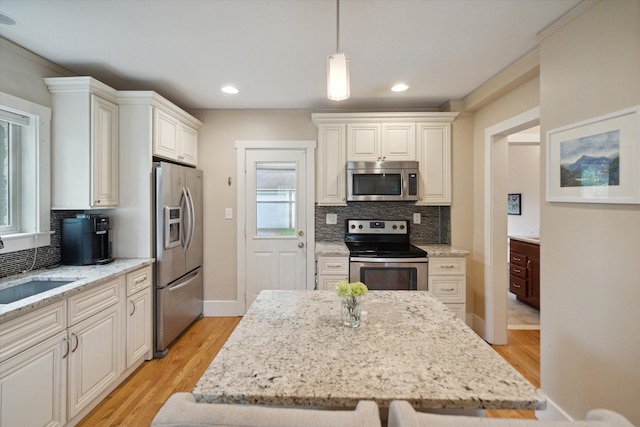 kitchen with stainless steel appliances, backsplash, light stone counters, light wood finished floors, and recessed lighting