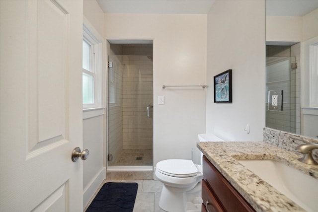 bathroom featuring a stall shower, toilet, vanity, and baseboards