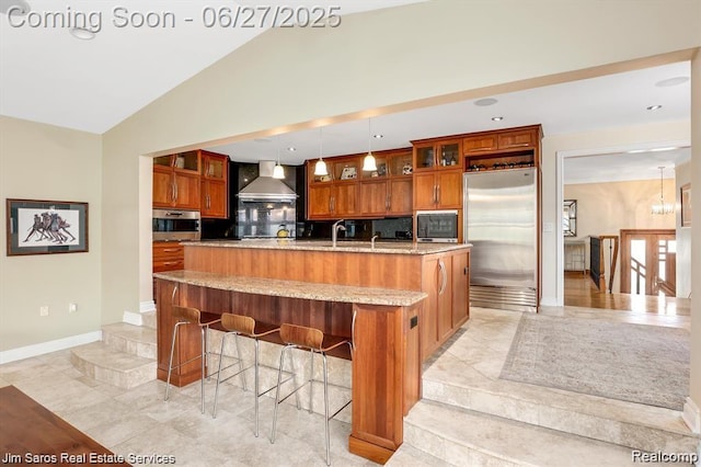 21838 Van K Dr, Grosse Pointe Woods, MI 48236 - kitchen featuring stainless steel appliances, wall chimney range hood, brown cabinetry, a spacious island, and tasteful backsplash