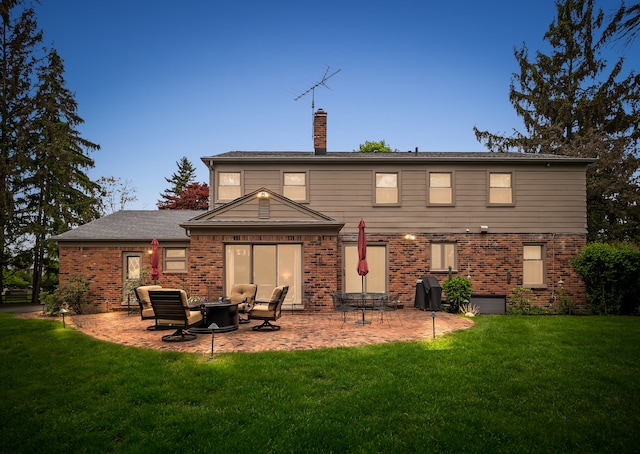 back of property with brick siding, a chimney, and a lawn