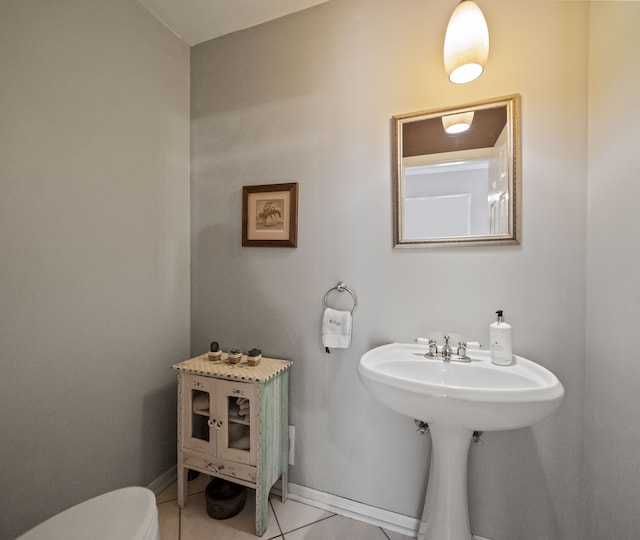 half bathroom featuring tile patterned floors, baseboards, and toilet