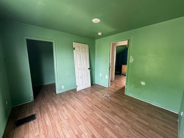 1143 Ballard St, Lansing, MI 48906 - unfurnished bedroom featuring wood finished floors, baseboards, a walk in closet, and a closet