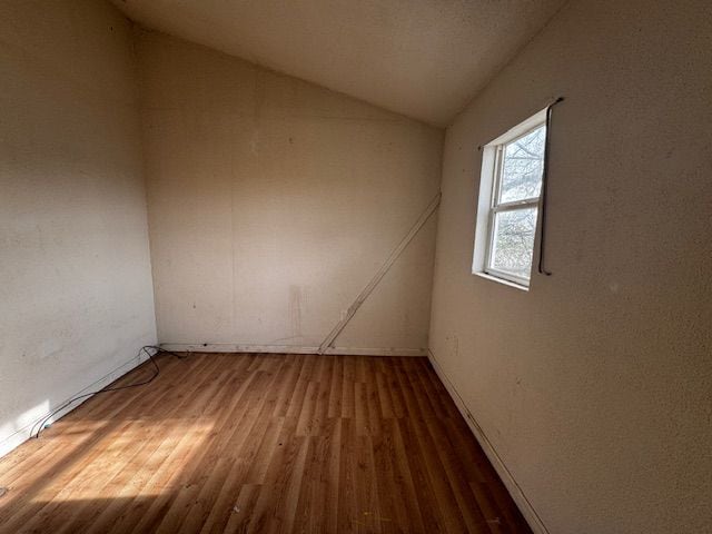 1143 Ballard St, Lansing, MI 48906 - empty room with wood finished floors, lofted ceiling, and baseboards