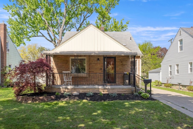 bungalow with a porch, stone siding, a front lawn, a chimney, and roof with shingles
