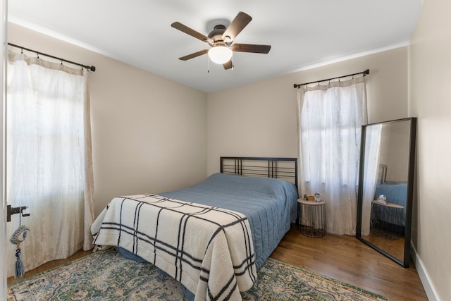 bedroom featuring multiple windows, wood finished floors, and ceiling fan