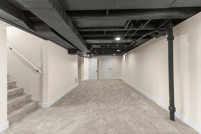 finished below grade area featuring carpet flooring, stairway, and baseboards