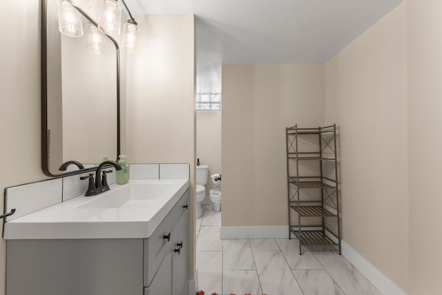 bathroom with toilet, vanity, marble look tiles, and baseboards
