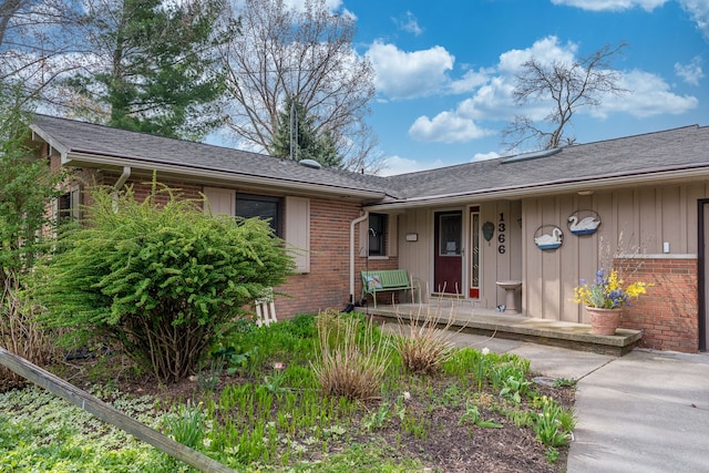 1366 E Coon Lake Rd, Howell, MI 48843 - doorway to property with brick siding, a porch, and a shingled roof