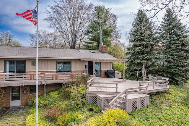 1366 E Coon Lake Rd, Howell, MI 48843 - back of house with brick siding, a shingled roof, a chimney, and a deck