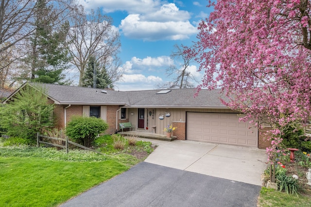 1366 E Coon Lake Rd, Howell, MI 48843 - ranch-style house featuring brick siding, an attached garage, concrete driveway, roof with shingles, and a front yard