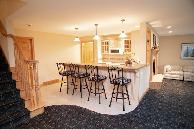 2865 Vw Ave E, Vicksburg, MI 49097 - kitchen featuring white microwave, baseboards, decorative backsplash, a breakfast bar area, and a peninsula