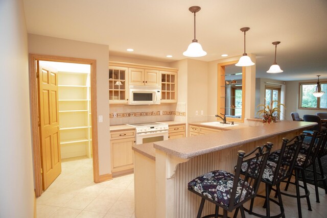 2865 Vw Ave E, Vicksburg, MI 49097 - kitchen with white appliances, a breakfast bar area, a sink, glass insert cabinets, and pendant lighting