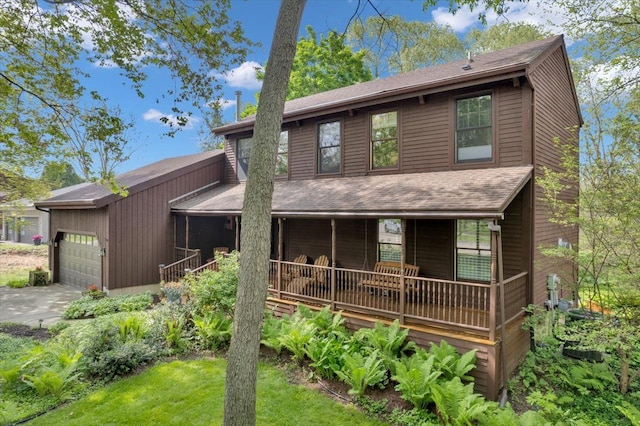 back of property with a garage, covered porch, concrete driveway, and a shingled roof