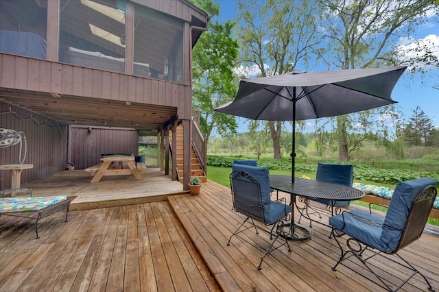 wooden terrace with outdoor dining area, stairway, and a sunroom