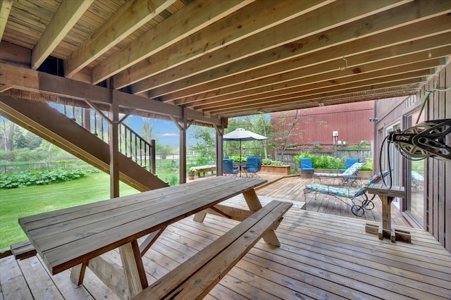 wooden terrace featuring outdoor dining area, stairway, and a yard