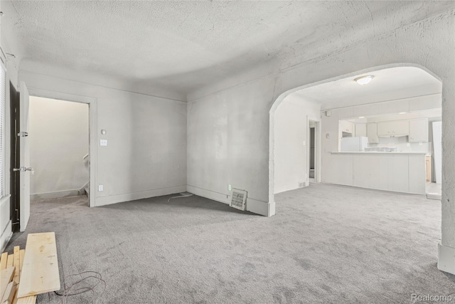 5856 Barrett St, Detroit, MI 48213 - unfurnished living room featuring arched walkways, carpet flooring, and a textured ceiling