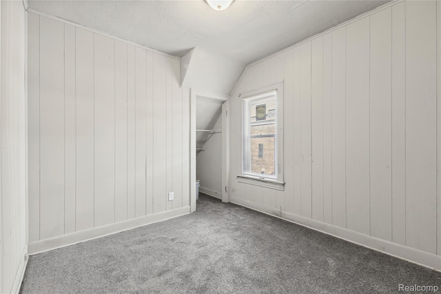 5856 Barrett St, Detroit, MI 48213 - unfurnished bedroom with vaulted ceiling, carpet floors, a closet, a spacious closet, and wooden walls