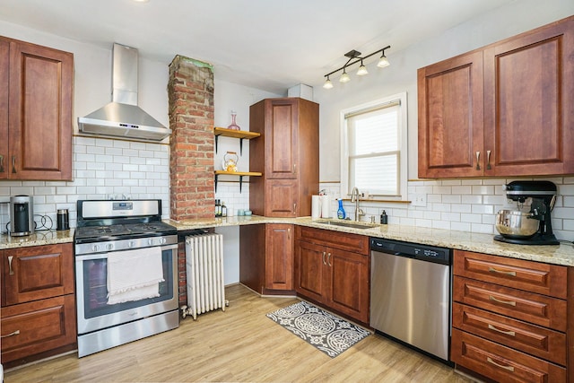 kitchen featuring appliances with stainless steel finishes, wall chimney exhaust hood, a sink, radiator heating unit, and open shelves