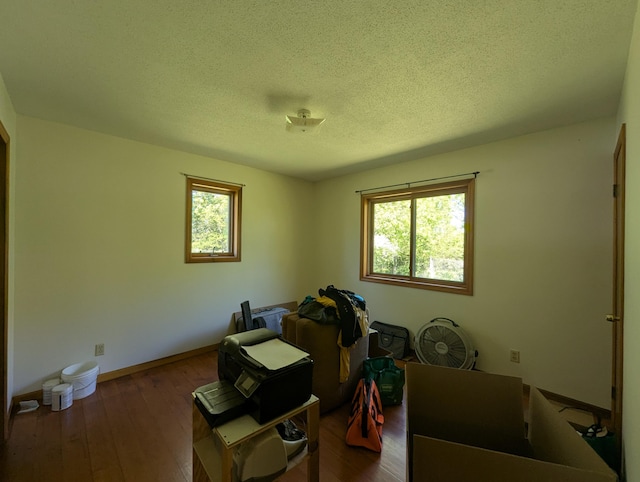 misc room with a textured ceiling, dark wood-style flooring, and baseboards
