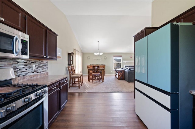215 Caribou Run, Dundee, MI 48131 - kitchen featuring appliances with stainless steel finishes, lofted ceiling, dark brown cabinetry, a chandelier, and decorative backsplash