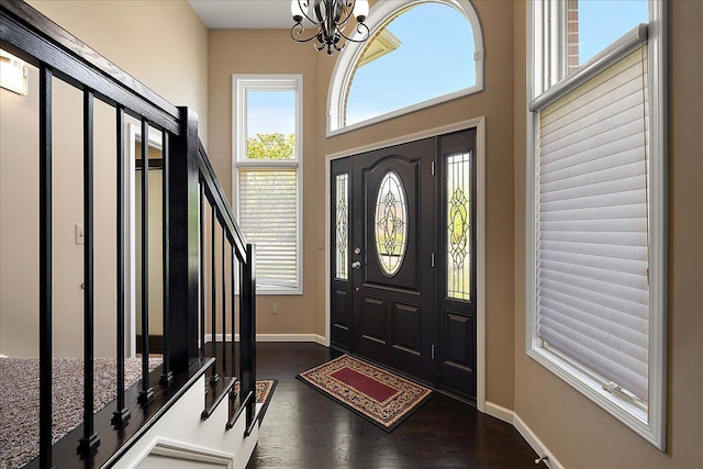 foyer with baseboards, a chandelier, dark wood-type flooring, and stairway