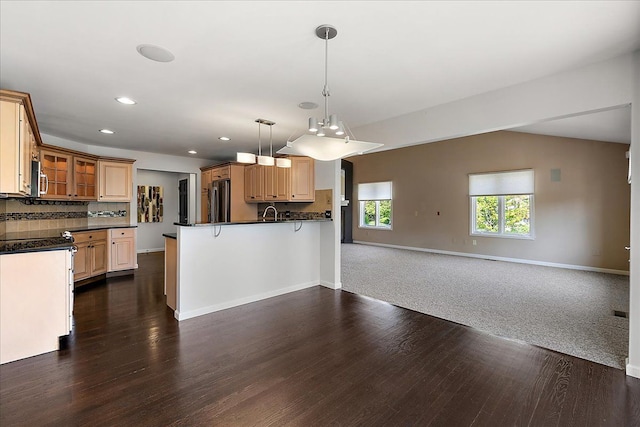 kitchen featuring open floor plan, dark countertops, glass insert cabinets, dark wood-style floors, and recessed lighting